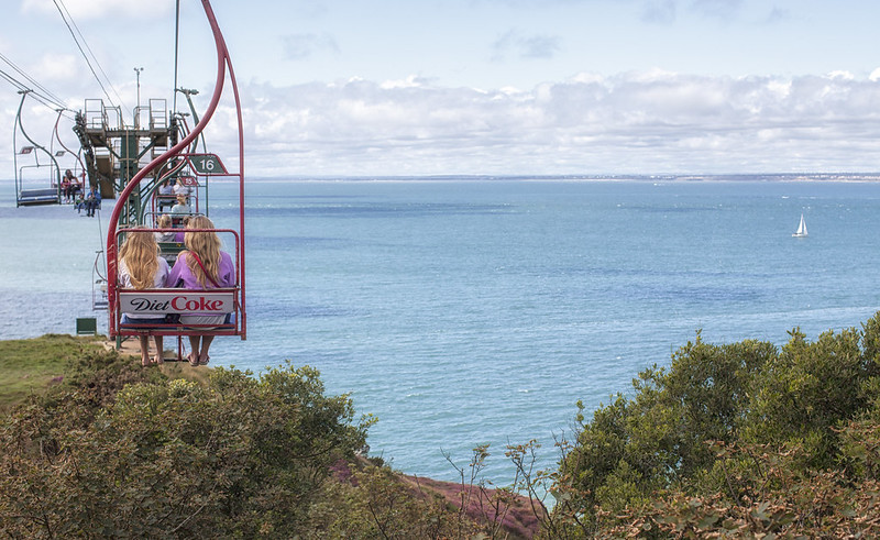 The iconic Needles Chairlift descending over Alum Bay, offering panoramic views of the Needles rocks and lighthouse on the Isle of Wight.