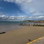 Totland Bay Beach on the Isle of Wight, showing a sandy shoreline, clear waters and views across the bay towards the coast.