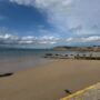 Totland Bay Beach on the Isle of Wight, showing a sandy shoreline, clear waters and views across the bay towards the coast.