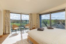 Master bedroom at Rena’s Retreat with double-aspect windows, private balcony, en-suite bathroom, and countryside views with glimpses of the sea