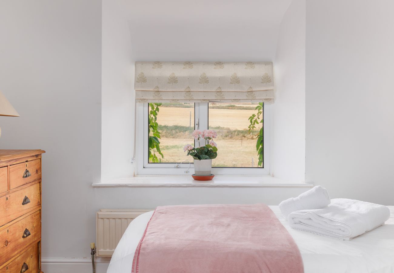 Comfortable beds with countryside views through the window at Moon Chine Cottage on the Isle of Wight.