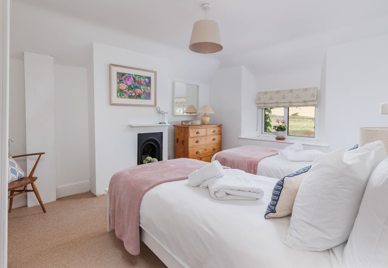 Beds and countryside views through the window in a bedroom at Moon Chine Cottage.s