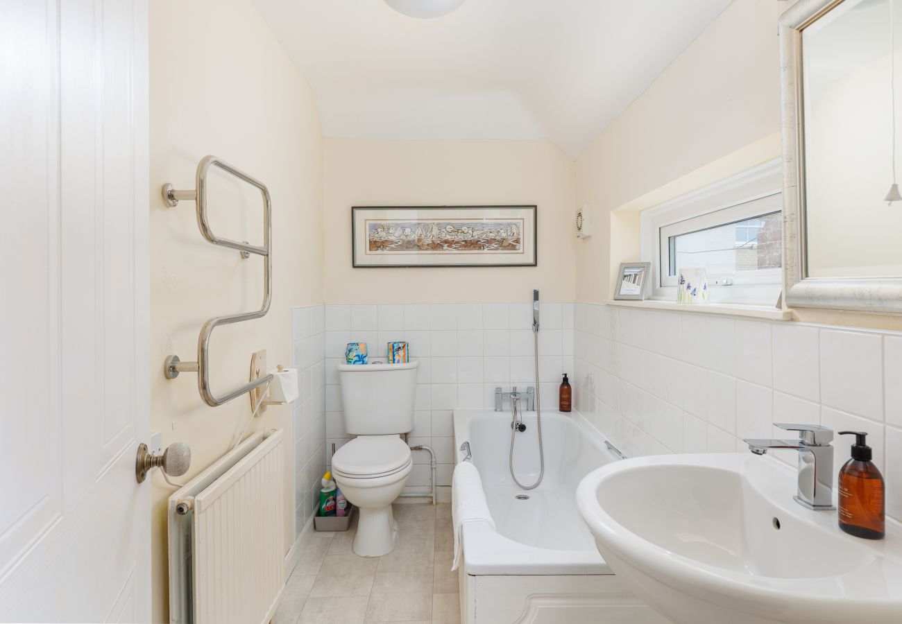 Bathroom with a bath and handheld showerhead at Moon Chine Cottage on the Isle of Wight.