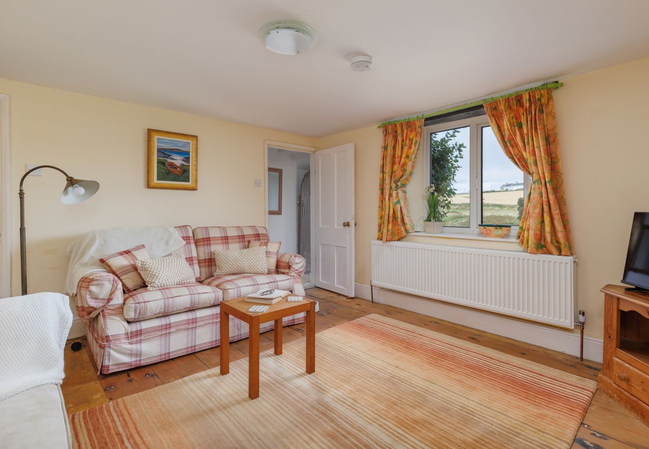 Cosy living room at Moon Chine Cottage with countryside views through the window.
