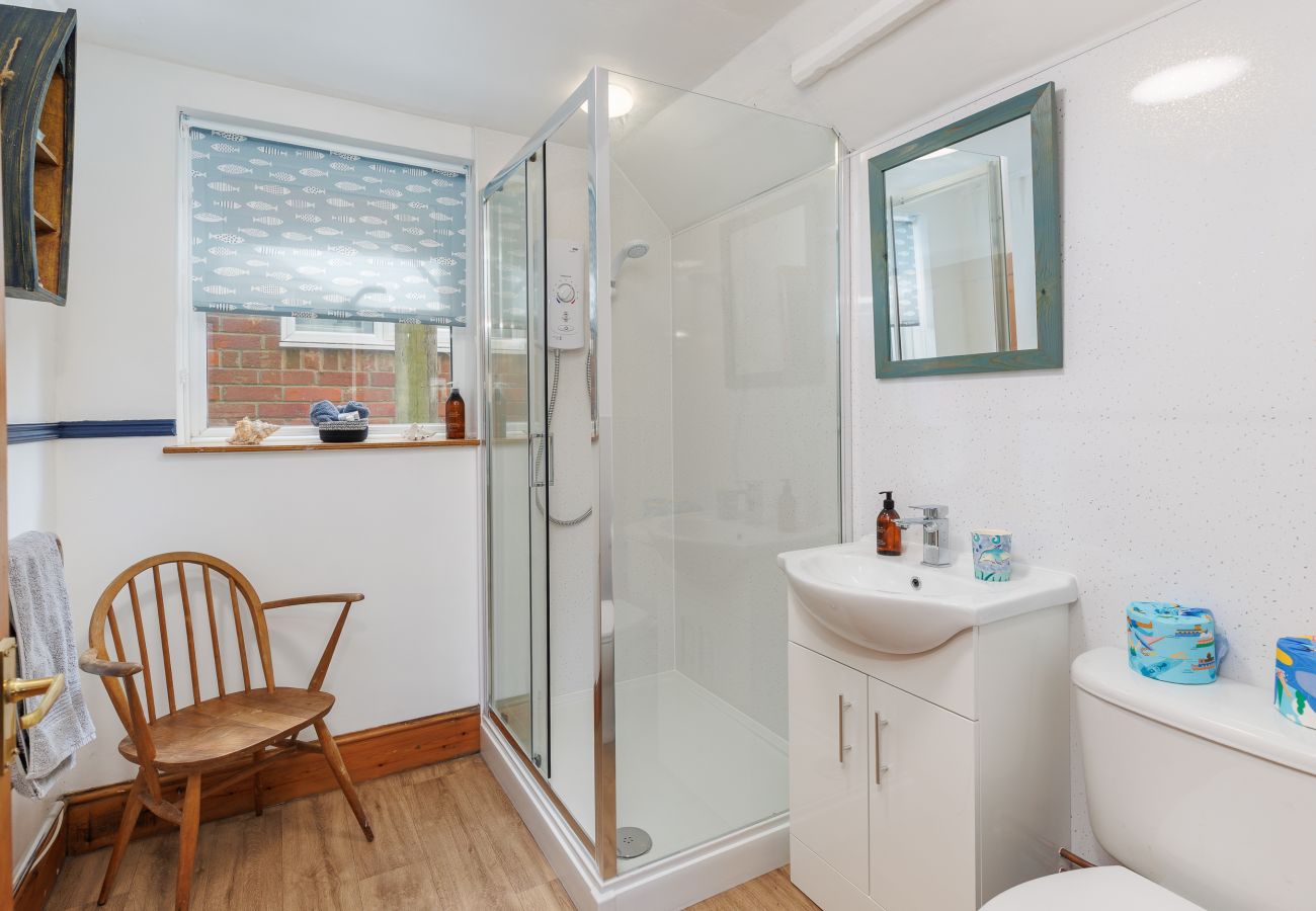 Downstairs bathroom with a shower at Moon Chine Cottage on the Isle of Wight.