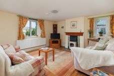 Cosy living room at Moon Chine Cottage with a TV, electric log burner and countryside views.