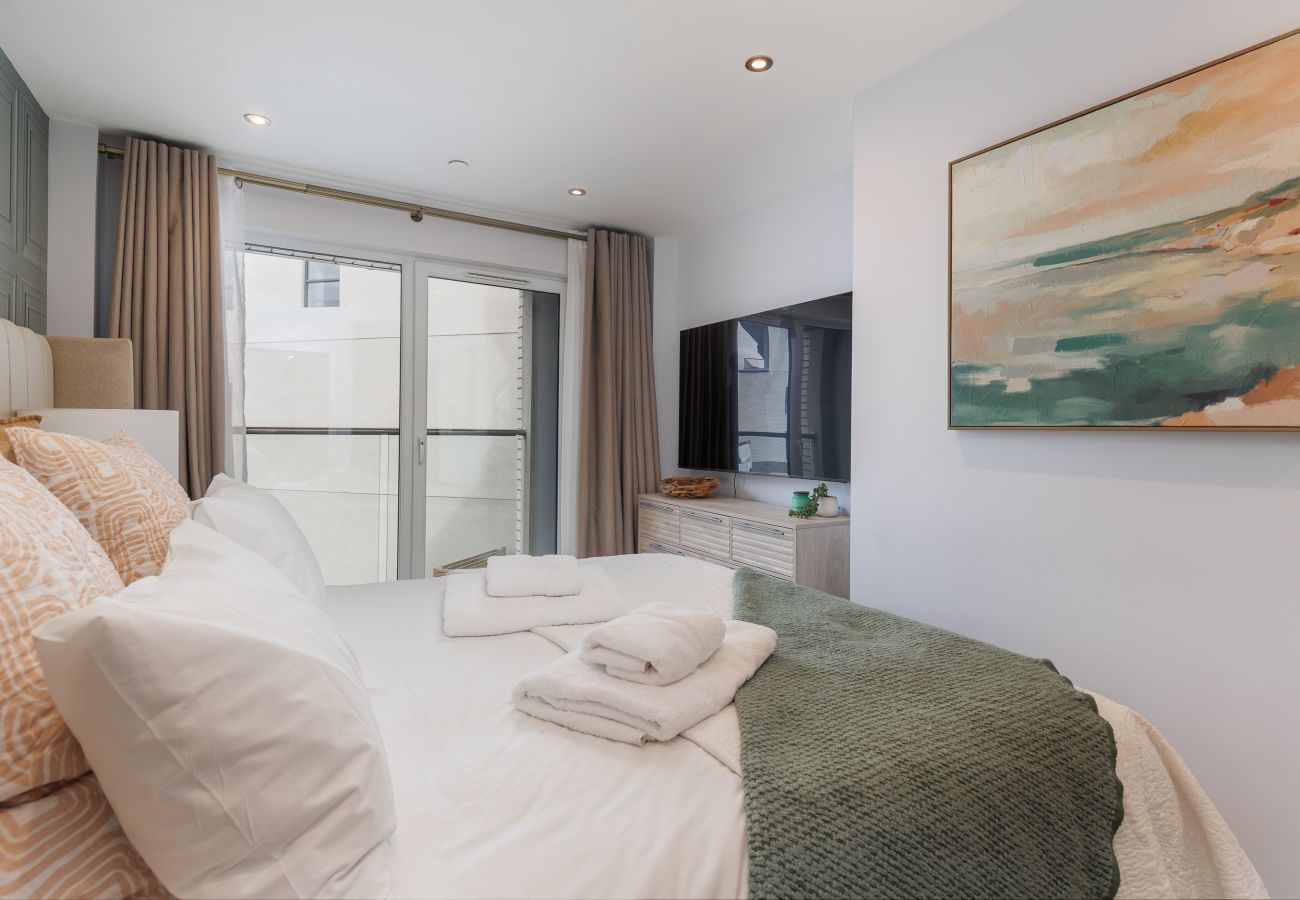 Master bedroom with a super king-size bed and balcony at Hummingbird, Sandown seafront.